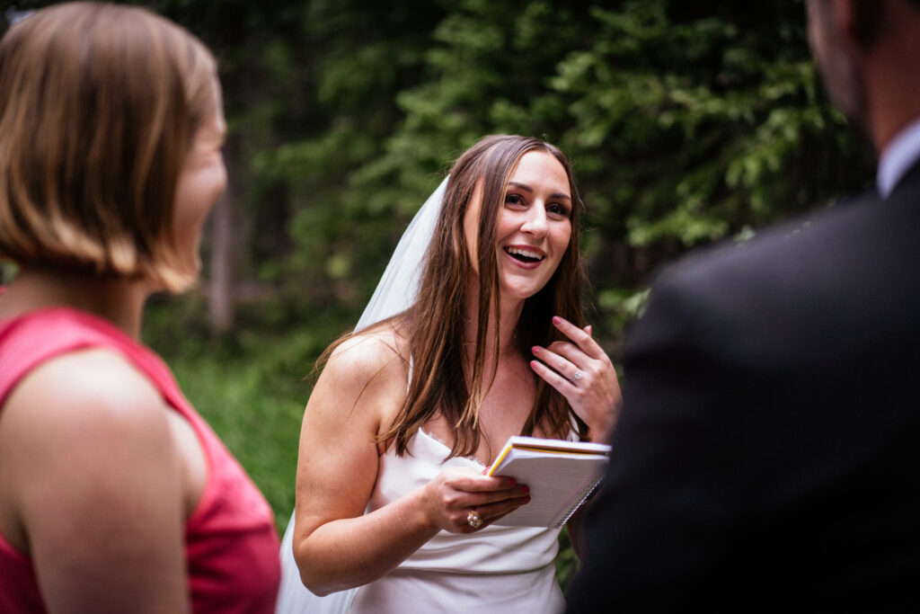 Bride smiling and crying while saying vows at Colorado elopement.