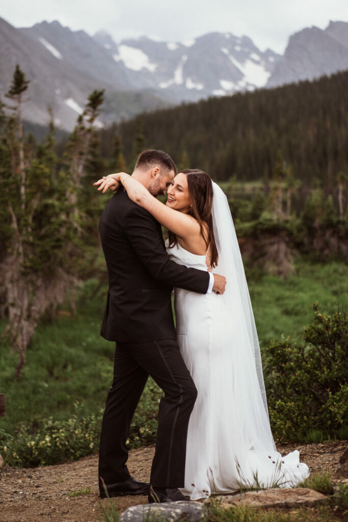 birde and groom in wedding clothes smiling and hugging at Indian Peaks, Colorado elopement at Brainard Lake.