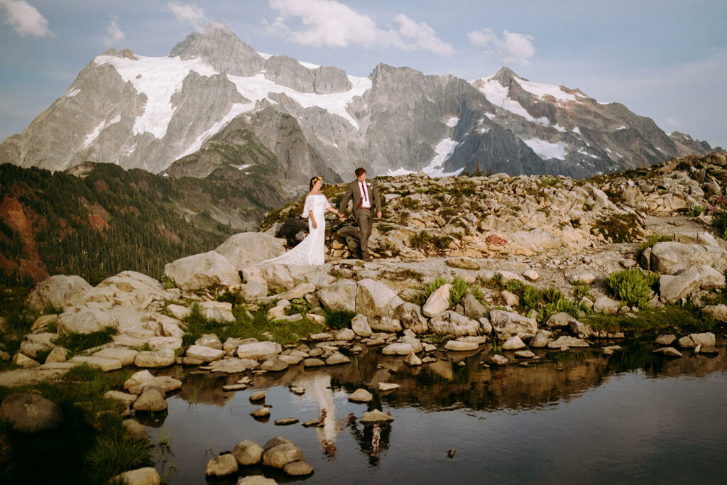 Couple in wedding clothes walking in front of mountains in article on how to elope in Washington state