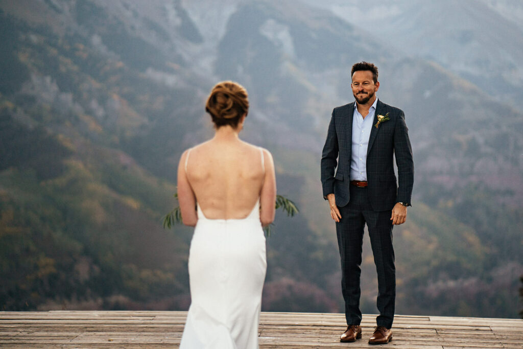 Groom smiling at bride as she walks down the aisle at Telluride, Colorado elopement at San Sofia overlook.