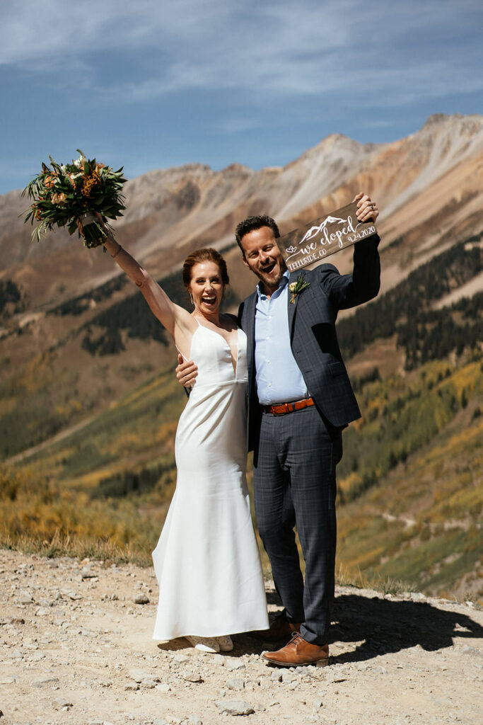 Bride and groom holding "we eloped" sign and celebrating at Telluride, Colorado elopement.