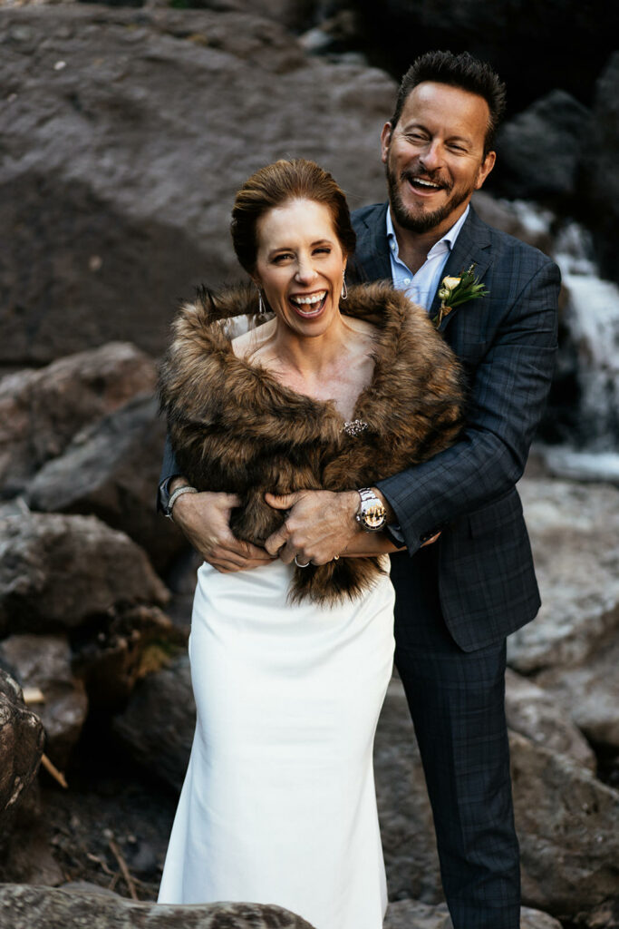 Smiling bride and groom at Bridal Veil Falls in Telluride.