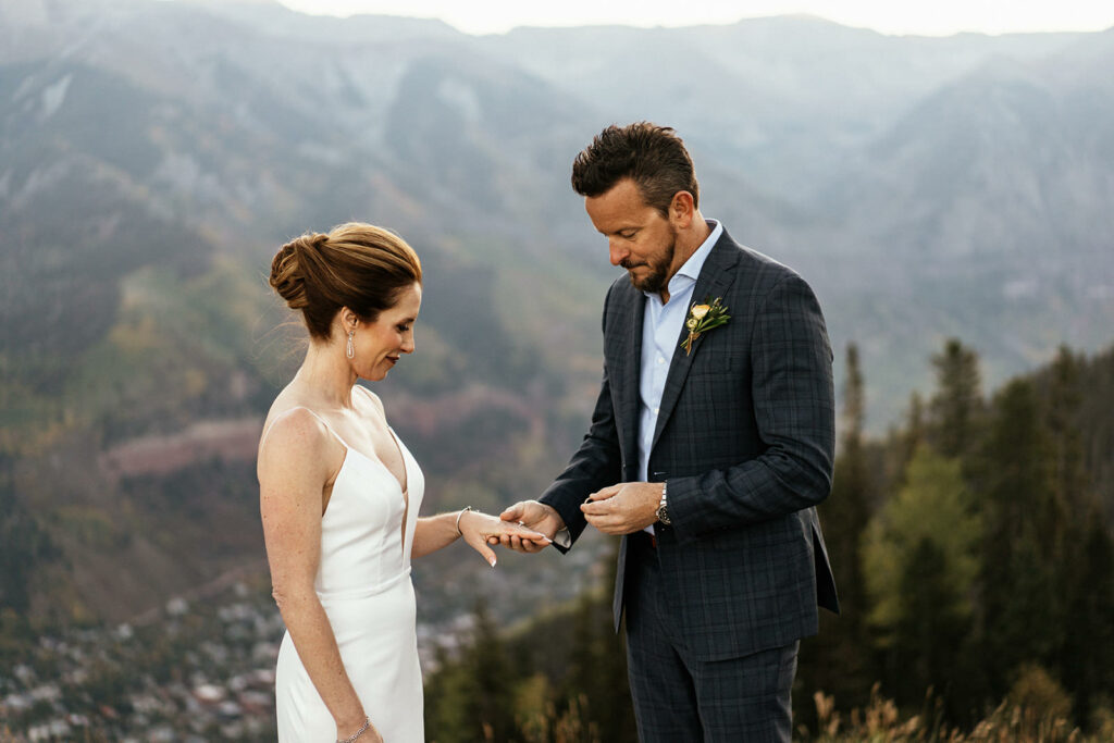 Groom putting ring on bride's finger at Telluride, Colorado elopement at San Sofia.
