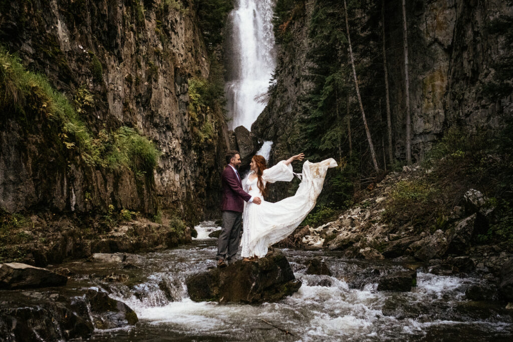 bride and groom in wedding clothes standing under waterfall at telluride colorado elopement by telluride elopement photographer