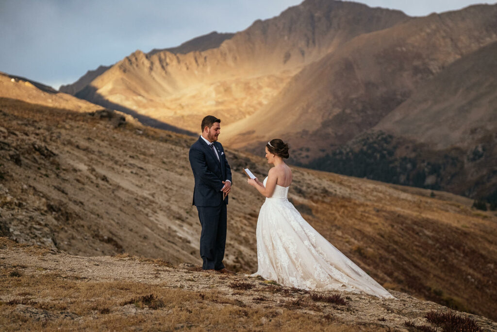 Bride and groom saying vows on top of mountain at sunset at Twin Lakes Colorado elopement
