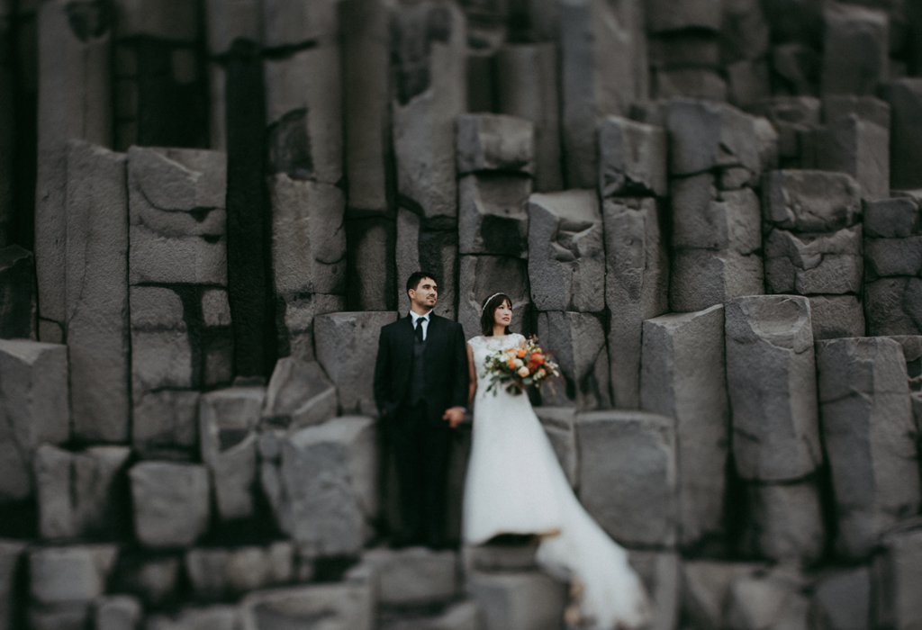 Bride and groom in wedding clothes standing on rock columns at Vik Iceland destination elopement