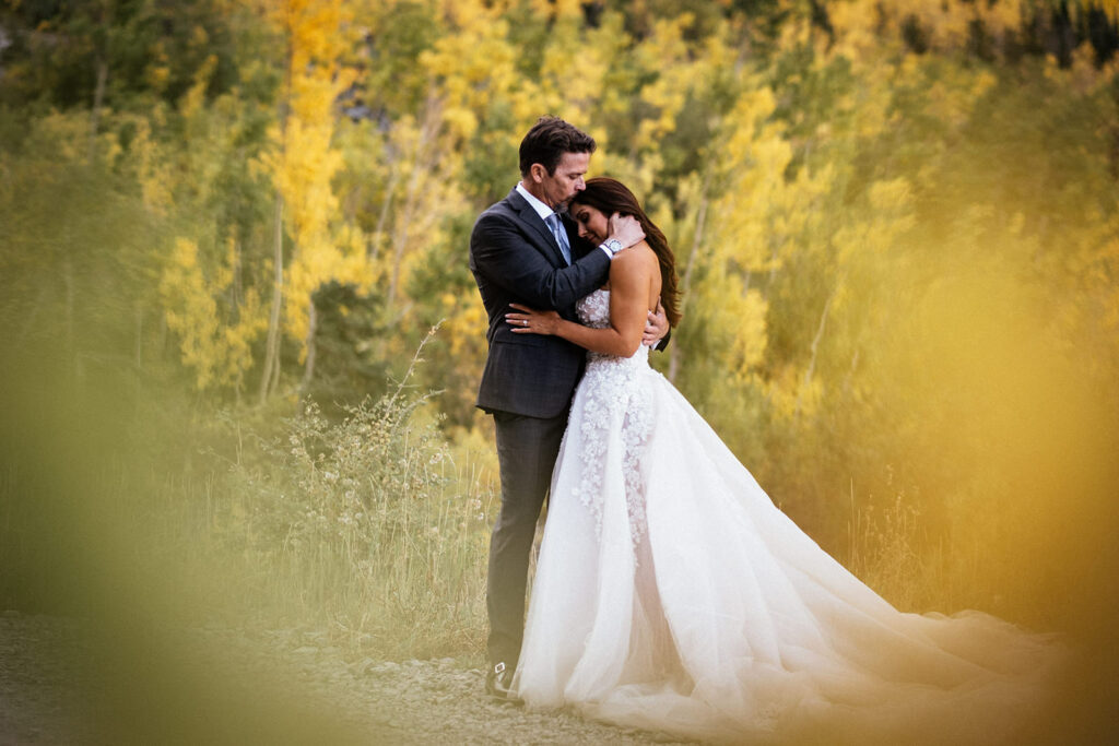 bride and groom in wedding clothes snuggle in grove of aspens at Bridal Veil Falls Elopement in Telluride, Colorado