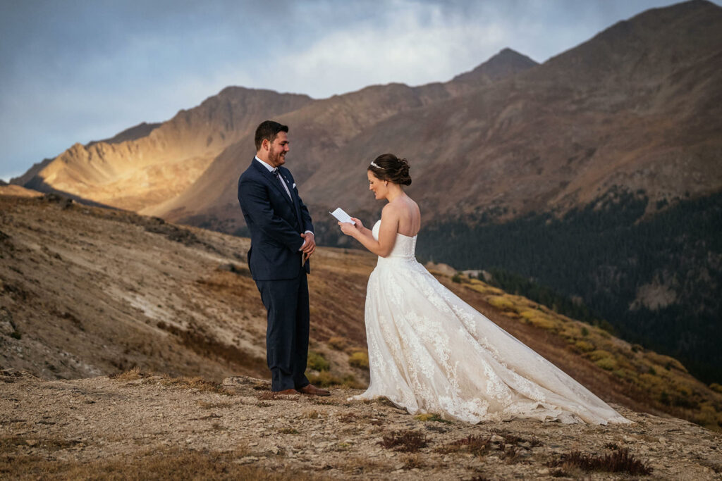 bride and groom in wedding clothes say vows on top mountain at colorado adventure elopement