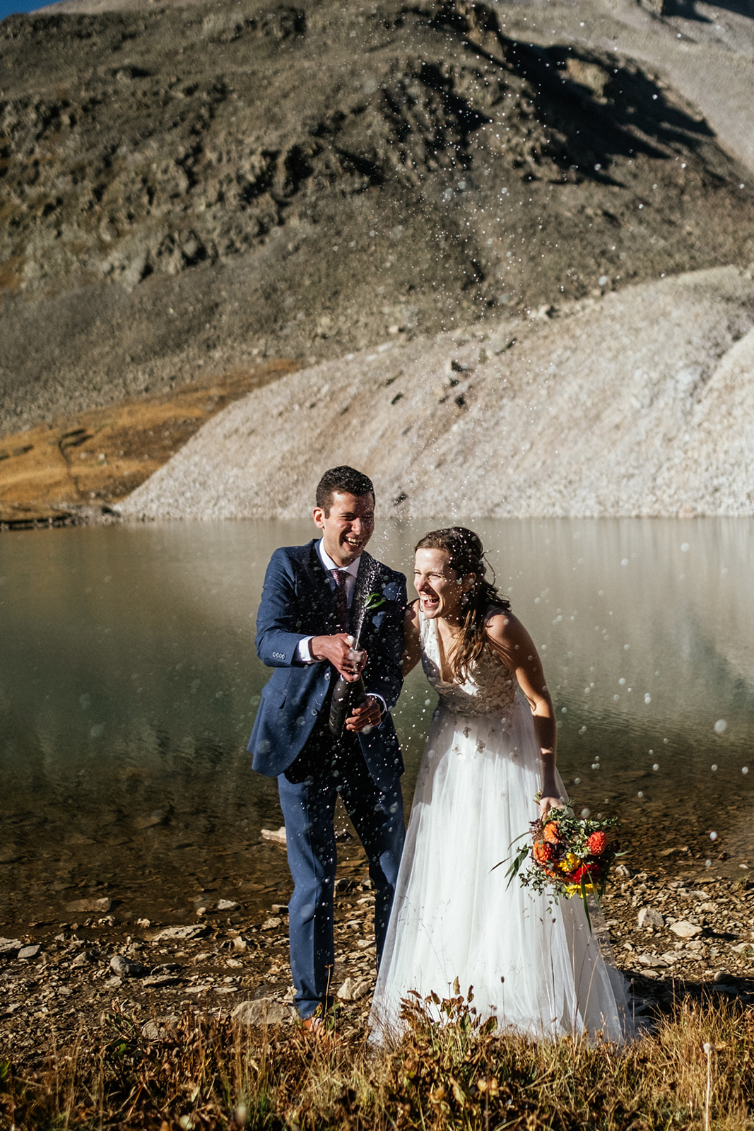 bride and groom popping champagne next to Alpine Lake at Telluride Colorado elopement