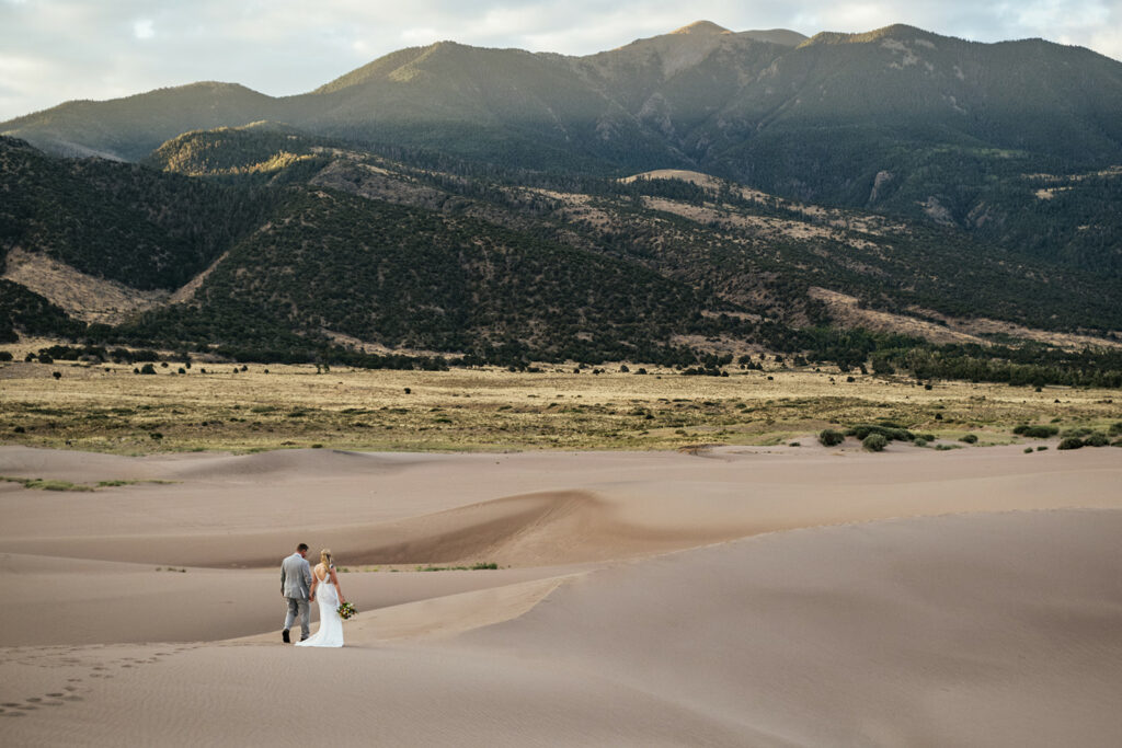 Bride and groom walk through sand dunes at Great Sand Dunes National Park elopement in Colorado
